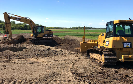 Dozer and excavator working on land clearing in a field